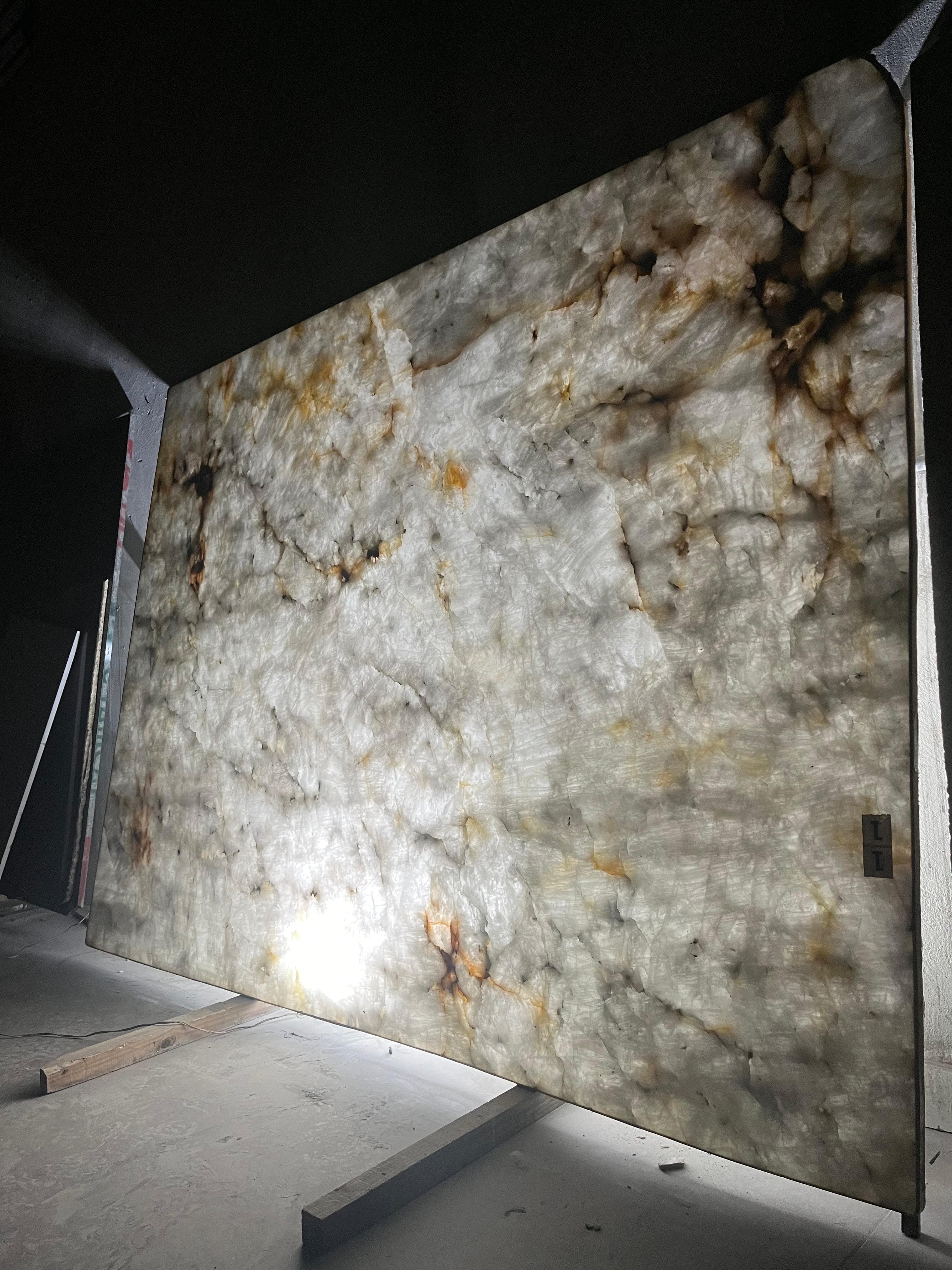 Chapa de pedra translúcida, provavelmente quartzito, iluminada por trás para revelar seus veios e cores.
